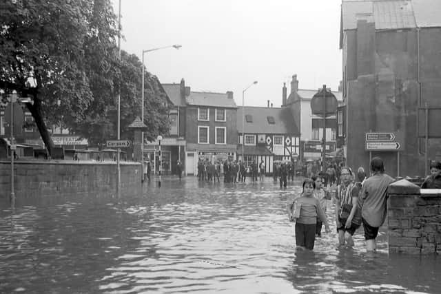 Children making the most of the rain while others watch on trying to keep dry.