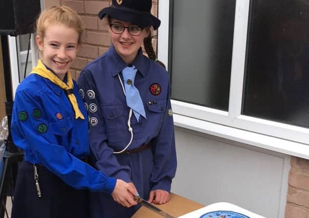 Kirkby Guides Izzy (left) and Zara in vintage uniforms help cut the celebratory cake