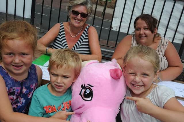 Daisy Taylor, 7, Tyler Lillian, 4 and 8 year old Madelane Barker try and guess the name of the giant unicorn on one of the stalls at the Emma Brown fundraiser with stall holders Chris Hunt and Karen Barker.