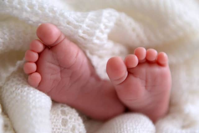A new born baby's feet are visible peeking out of a shawl