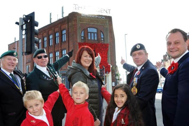 Brian Dykes, left, chairman of the Kirkby branch of the RBL, their vice-chairman Len Dooley, Claire Lilley from Artful Buttoner, veteran Richard Kirk and Jason Zadrozny the Leader of Ashfield District Council, with Annesley Primary School pupils, Charlie, Christian and Rajpreet, pictured after the unveiling of the cascade of poppies on The Regent Wetherspoon pub in Kirkby on Friday.