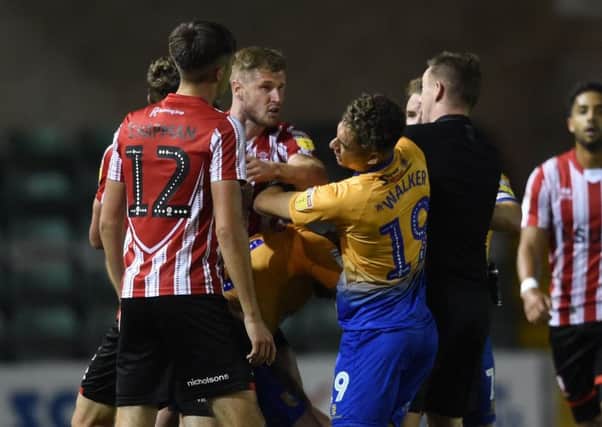 Stags' Tyler Walker tries to defend his teammate Callum Butcher from Imps' Michael O'Connor as tempers rise in Mansfield's win at Lincoln in the Checkatrade Trophy in September.