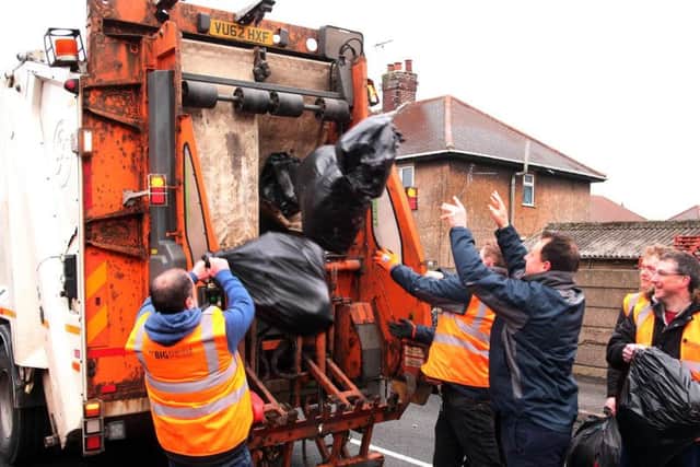 Leader of Ashfield district council Jason Zadrozy and council employees throw the litter into the refuse lorry.