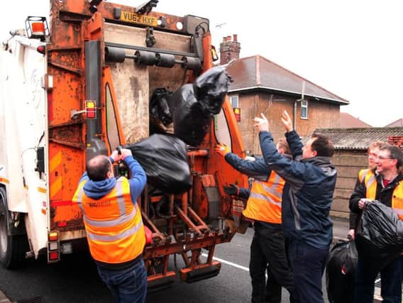 Leader of Ashfield district council Jason Zadrozy and council employees throw the litter into the refuse lorry.
