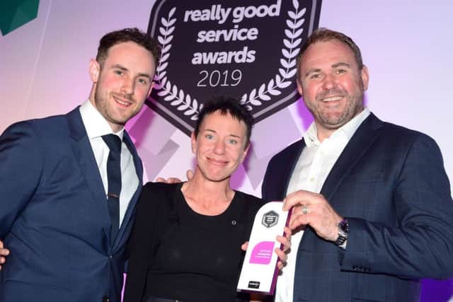 Caroline Webster receives her award from rugby legend Scott Quinnell (right) and Tom Morgan, of trentbarton.