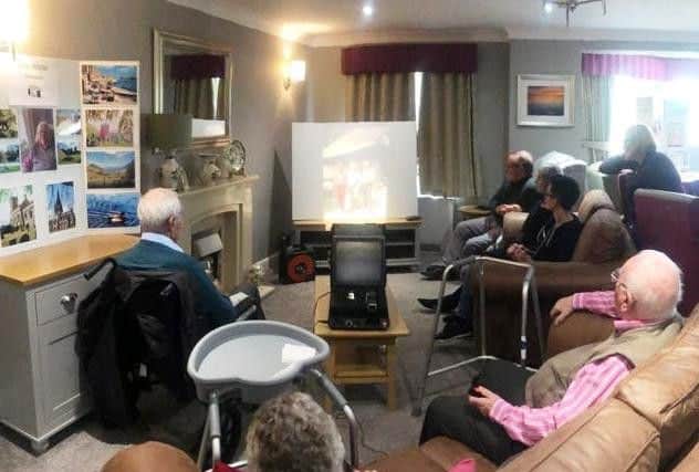 Peter White, in a pink and white shirt, showing his pictures.