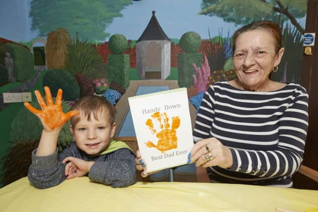Oliver Iglinski gets help from resident Carol Warren with his Father's Day card.