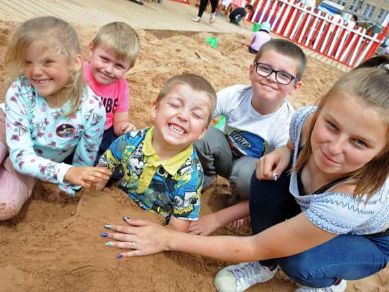Alfie Whitehead lets his siblings and cousins plant him in the sand,from left, Brooklyn-Gray Whitehead,Harrison Hyatt, Braidon Whitehead,  and 12 year old Chardonnay Hyatt at last year's beach