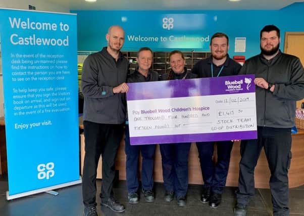 Workers from the Castlewood team present a cheque to Bluebell Wood.