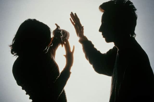 MODEL RELEASED. Domestic violence. Silhouette of a woman protecting herself from a blow from her partner by holding her arms in front of her face.