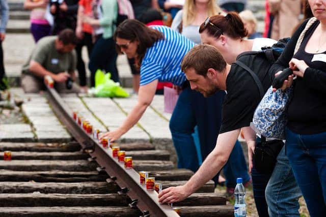Visitors with the Holocaust Educational Trust place candles on the track at Auschwitz II follwoing the memorial service.