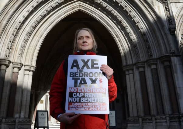 A protester against the government's "bedroom tax" demonstrates outside the High Court in London. PRESS ASSOCIATION Photo. Picture date: Friday February 21, 2014. The Court of Appeal has upheld the legality of Government cutbacks in the benefits system. Judges rejected accusations that the so-called "bedroom tax" unlawfully discriminates against the disabled. See PA story COURTS Cuts. Photo credit should read: Stefan Rousseau/PA Wire