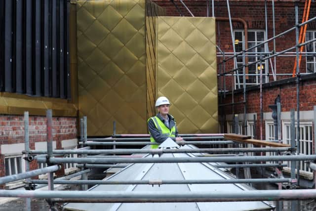 James Henderson with some of the external 'bronze' cladding. Picture by Jonathan Gawthorpe