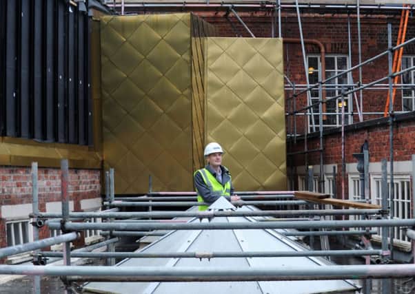 James Henderson with some of the external 'bronze' cladding. Picture by Jonathan Gawthorpe