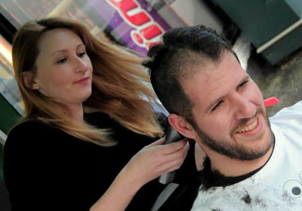 Emma Shucksmith of 'Classic hair & Beauty' Mansfield cuts off half the hair and beard belonging to Theo Keliris of  Mansfield's Black Pearl fish and chip shop