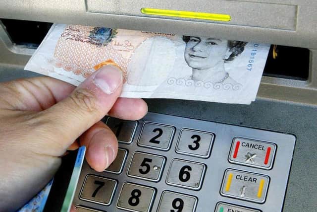 Embargoed to 0001 Wednesday June 13.File photo dated 04/04/06 of a person withdrawing money from a cashpoint. PRESS ASSOCIATION Photo. Issue date: Wednesday June 13, 2012. People will be able to donate money to charities including Cancer Research UK, Barnardo's and Age UK at the same time as withdrawing cash at thousands of ATMs from this week. More than 8,000 cash machines across the Royal Bank of Scotland (RBS) group network have been enabled to accept donations of between £1 and £150 to eight charities. See PA story MONEY Charity. Photo credit should read: Gareth Fuller/PA Wire