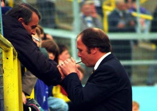 Mansfield Town Manager Andy King gets a light for his cigar from a Gillingham fan before the game at the Priestfield Stadium, Gillingham, in 1995. Picture by Dan Westwell.