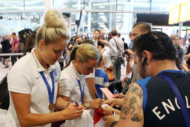 Steph Houghton signs autographs as the England women's team arrive back at Heathrow Airport after the 2015 FIFA Women's World Cup in Canada. Photo credit: Steve Parsons/PA Wire