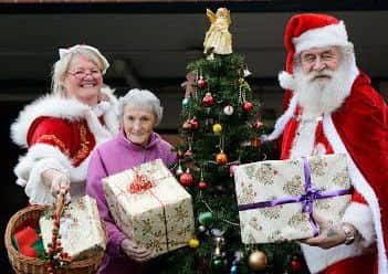 Resident Joan Lane receives her present from Mr and Mrs Claus at Herbert Buzzard Court.