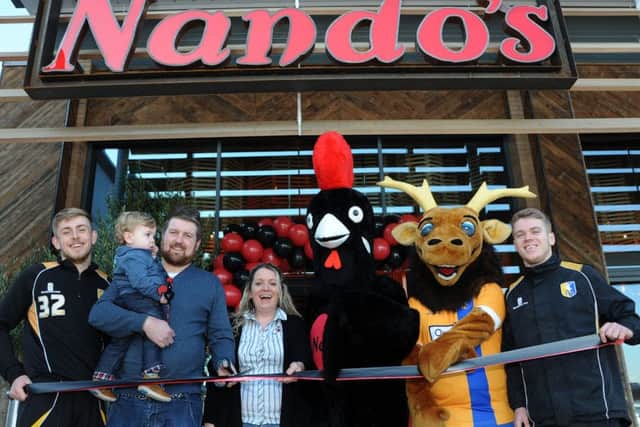 Craig Moody, pictured with his son Henry, cuts the ribbon to officially open the new Nando's restaurant on the Park Lane Leisure Park on Wednesday, also pictured are from left, the Stag's Connor Green, manager, Nicole Gardiner-Crehan, Barcy and Sammy, mascots for Nando's and the Stags and Danny Fletcher.