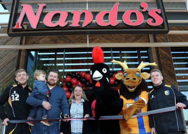 Craig Moody, pictured with his son Henry, cuts the ribbon to officially open the new Nando's restaurant on the Park Lane Leisure Park on Wednesday, also pictured are from left, the Stag's Connor Green, manager, Nicole Gardiner-Crehan, Barcy and Sammy, mascots for Nando's and the Stags and Danny Fletcher.