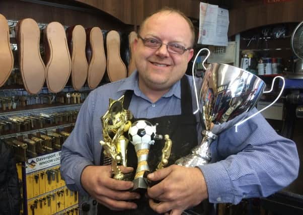 David Lee, manager of Mansfield's Quality Shoe Repairs & Key Cutting Services, with some of the trophies which could be won.