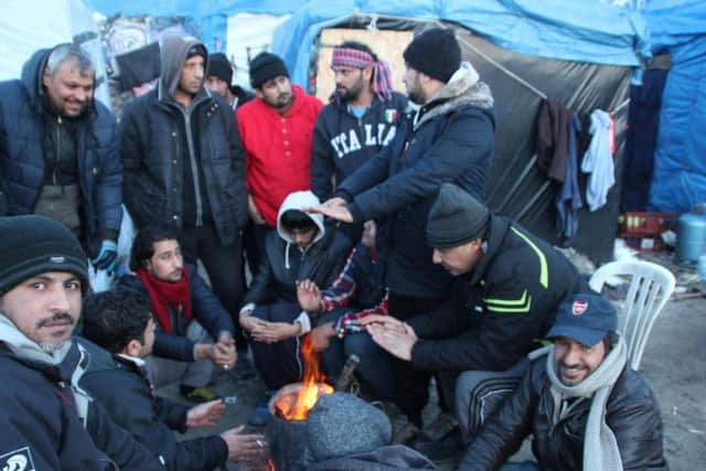 A group of men huddled around a fire in the Calais Jungle, image by Malachy Browne (CC).