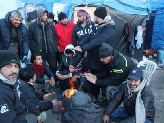 A group of men huddled around a fire in the Calais Jungle, image by Malachy Browne (CC).