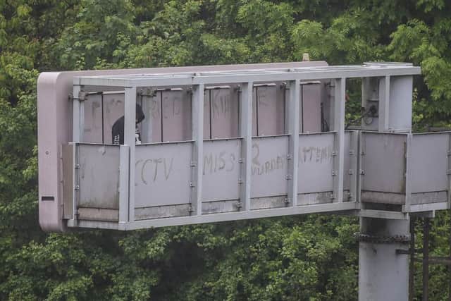 A man on who climbed a motorway information board has been arrested and is still in police custody. (Image: SWNS).
