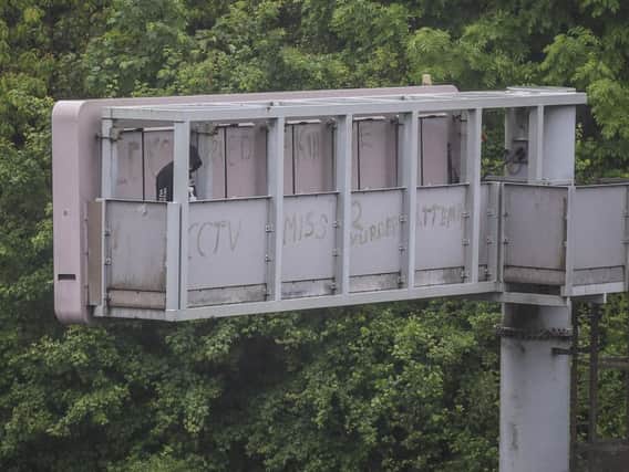 A man on who climbed a motorway information board has been arrested and is still in police custody. (Image: SWNS).