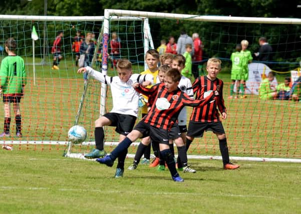 GOALMOUTH SCRAMBLE -- a battle for the ball in front of goal as the action hots up during Priory Celtics annual tournament.