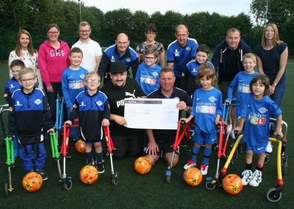 Dane Arnold (wearing cap) presents coach John Cheetham with a cheque after raising Â£5739 to Rolls Royce Leisure Frame Football.