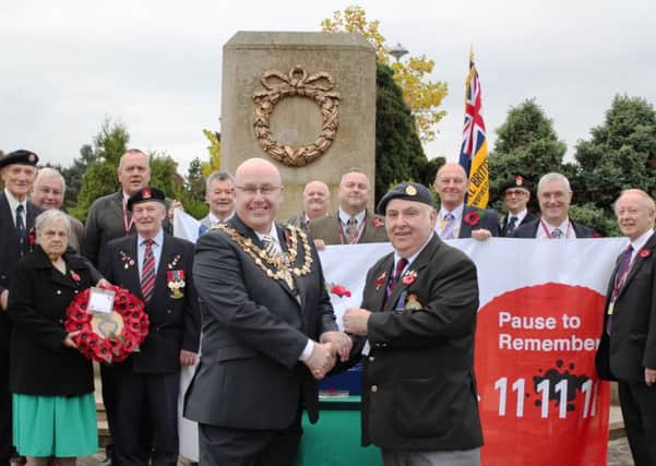 TIME TO REMEMBER -- the Deputy Mayor of Mansfield, Coun Mick Barton, presents the first poppy to appeal organiser, Joe Martin, watched by veterans.