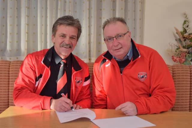 Manager Rudy Funk signs on the dotted line, watched by AFC Mansfield chairman Andy Saunders.