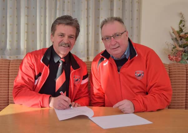 Manager Rudy Funk signs on the dotted line, watched by AFC Mansfield chairman Andy Saunders.