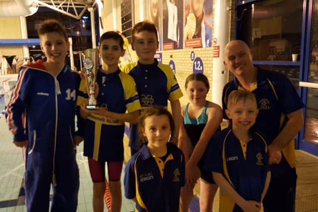 Some of the successful swimmers with the trophy and head coach Barry Tindall.