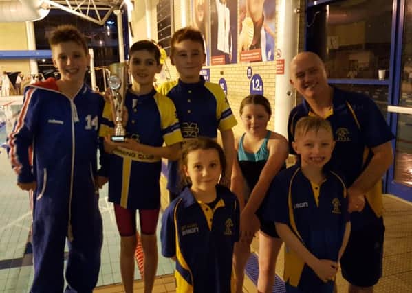 Some of the successful swimmers with the trophy and head coach Barry Tindall.