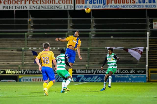 Mansfield Town's Rhys Bennett heads clear - Photo by Chris Holloway