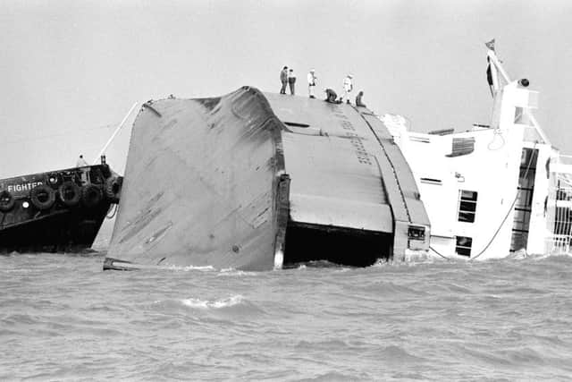 Rescue workers stand on the side of the half-submerged car ferry Herald of Free Enterprise which capsized off the Belgian port of Zeebrugge.