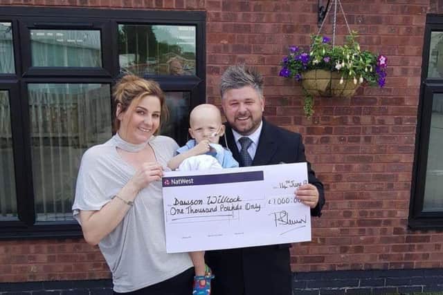 Wendy Willcock and son  Dawson are presented with a cheque for Â£1,000 by Paul Brown of Wass funeral directors.