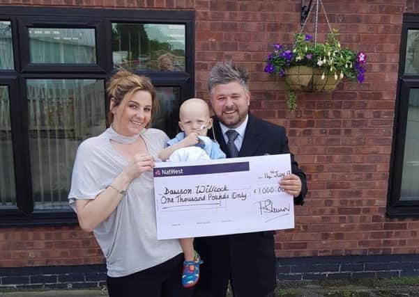 Wendy Willcock and son  Dawson are presented with a cheque for Â£1,000 by Paul Brown of Wass funeral directors.