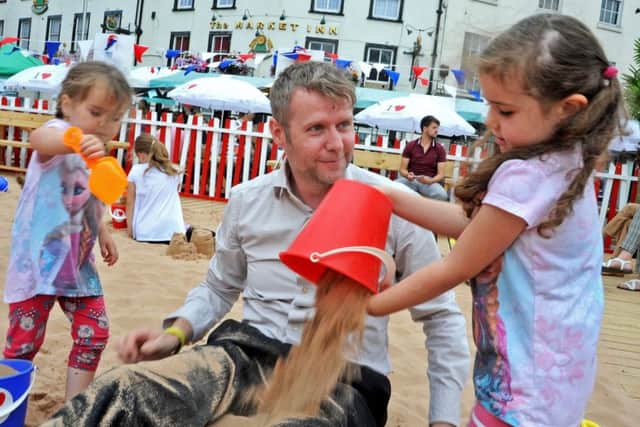 Phil Wadley joins in the fun with daughters Olivia and Isabella when the two tried to make him into a human sandcastle at Mansfield Market Place's beach.