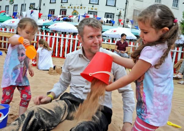 Phil Wadley joins in the fun with daughters Olivia and Isabella when the two tried to make him into a human sandcastle at Mansfield Market Place's beach.
