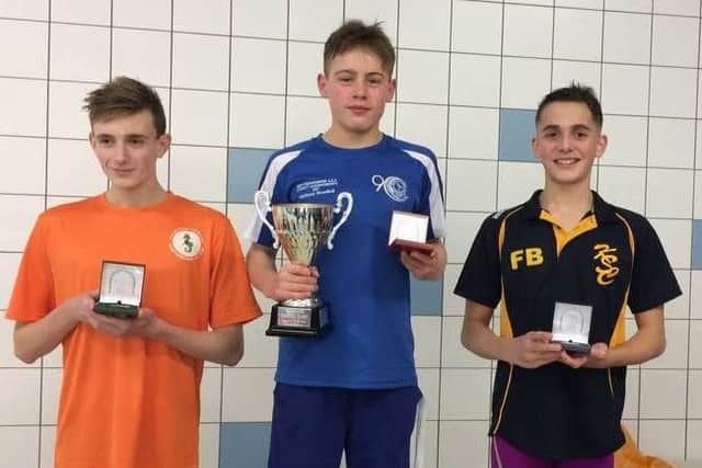 Matthew Woodhall (centre) on the podium after winning the 50m breaststroke junior championship trophy.