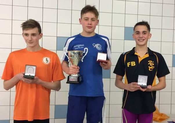 Matthew Woodhall (centre) on the podium after winning the 50m breaststroke junior championship trophy.
