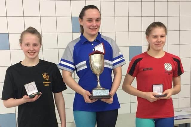 Champion Chloe Peach on the podium with her trophy after winning the senior 100m backstroke county title.