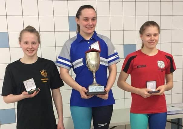 Champion Chloe Peach on the podium with her trophy after winning the senior 100m backstroke county title.