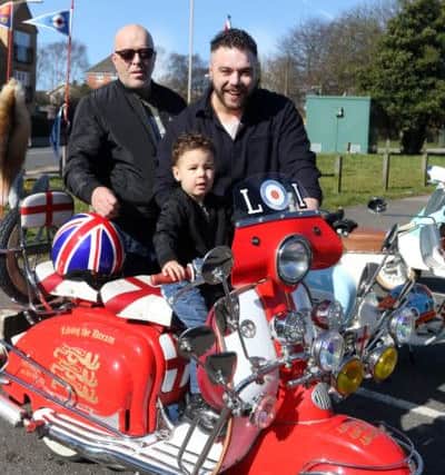Declan Slater rides the scooter watched by dad Adam and grand dad Shane.