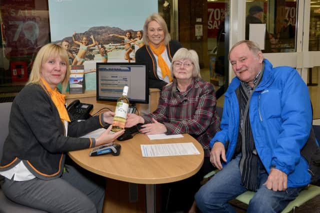 First customers John and Marlene Anthony recieve a bottle of bubbly from travel consultant Karen Widdowson and manager Christie Fulleylove at the rebranded Thomas Cook store.