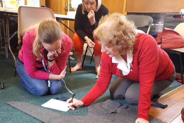 Professional costumier Anne Ryan speaking to some of the sewing volunteers about the design of a tunic.